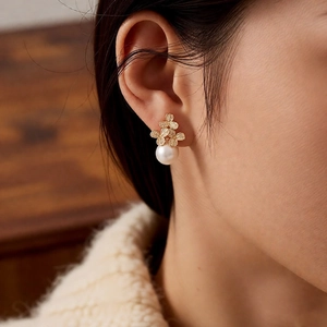 Makroaufnahme von Blumen-Zirkon-Perlenohrring am Model mit eleganten Gold-Blütenblättern