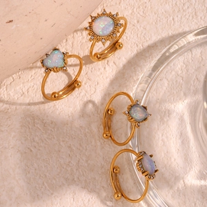 Close-up of four gold adjustable opal rings featuring sun and heart shapes with crystals