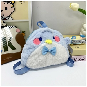 Detailed view of soft blue plush penguin backpack with a bow in a cute desktop setting