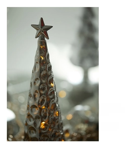 Macro shot of a glowing glass Christmas tree with LED lights and silver star topper