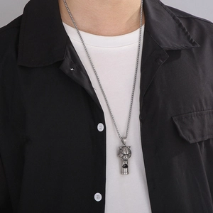 Close-up of a silver titanium steel lion head whistle pendant necklace worn by a model