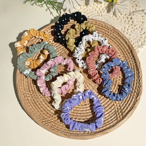 Detailed view of nine colorful satin scrunchies with floral patterns in a woven tray