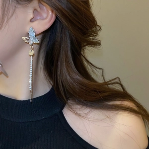 Détail d'une boucle d'oreille papillon élégante avec pompon en strass sur un modèle