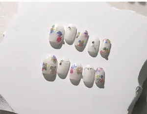 Detail of handmade press-on nails with white flowers and pearls on white stone slab