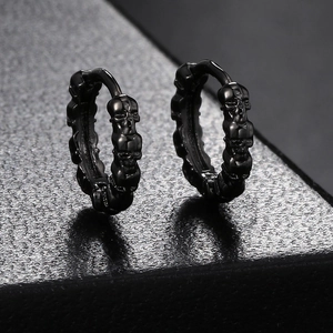 Close-up of black punk skull earrings with vintage gothic relief on textured surface