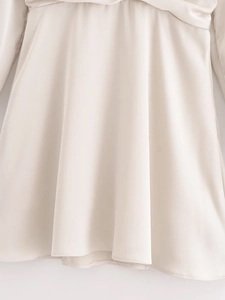 Detailansicht des cremefarbenen Satin-Kleidstoffs mit Hochglanz-Textur und Saumverarbeitung