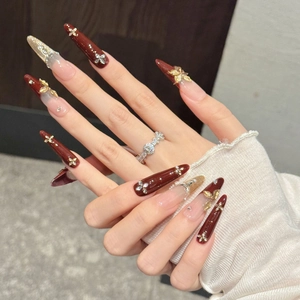 Faux ongles stiletto longs avec nœuds dorés 3D et strass brillants pour une manucure