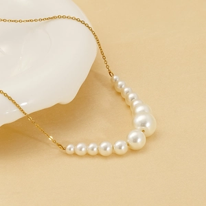 Elegant gold chain necklace with 11 gradient pearls on a soft textured background