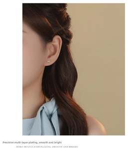 Close-up of polished silver bow stud earrings worn by a model in a lifestyle setting