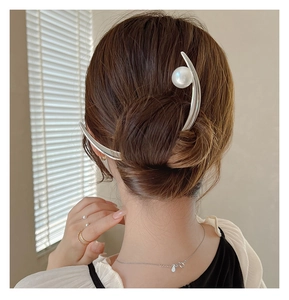Detail of elegant silver moon hair pin with a round pearl used in a stylish bun hairstyle