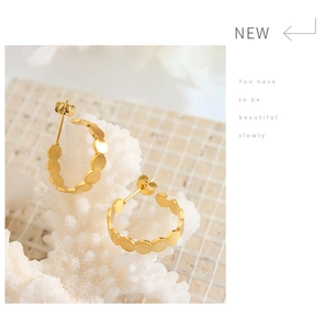 Golden C-shaped earrings with circular link design displayed on white coral background