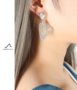 Close-up of woven hollow heart earrings in stainless steel on a model's ear