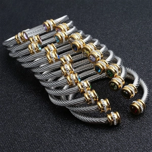 Close-up of twisted stainless steel cable bracelets with colorful gemstones and gold caps