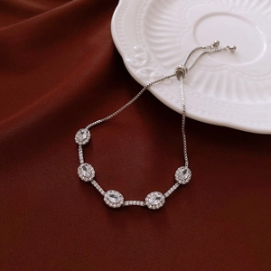 Detail of adjustable silver flower bracelet with five zircons on a white ceramic plate
