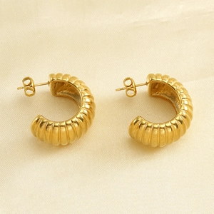 Boucles d'oreilles créoles torsadées dorées à l'or 18 carats sur fond de soie