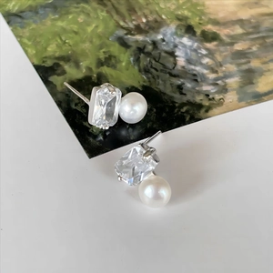 Close-up of S925 silver stud earrings featuring square zircon and round white pearl