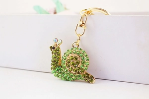 Detailed view of the cute snail keychain with green rhinestones on golden metal base