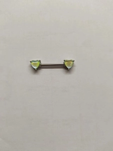Dettaglio delle estremità a forma di cuore verde chiaro su un piercing al capezzolo
