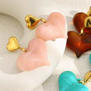 Vue détaillée de boucles d'oreilles cœur dorées avec texture en résine marbrée