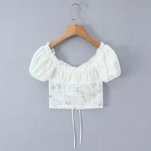 Détail d'un crop top en dentelle blanche avec col carré, manches bouffantes et broderies