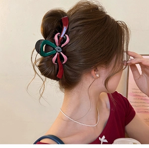 Détail d'une pince à cheveux colorée en forme de nœud portée sur cheveux longs