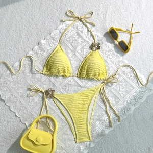 Detail of yellow bikini with textured fabric, metal flower accents, and pearl beads