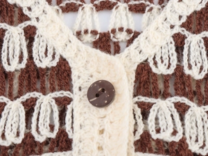 Close-up of hollowed-out crochet knit vest featuring wooden buttons and V-neck detail