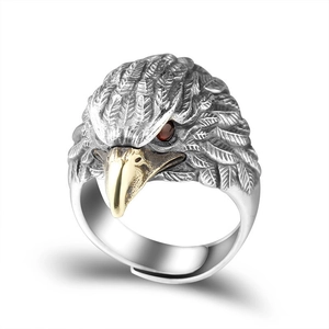 Macro detail of eagle ring featuring silver feathers, golden beak and red gemstone eyes