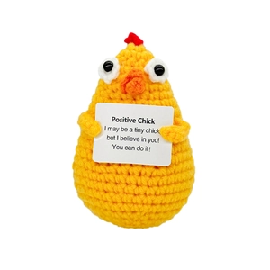 Close-up of handmade yellow crochet chick holding a positive inspirational card