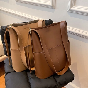 Detailansicht der khakifarbenen und braunen Leder-Tote-Bags mit minimalistischem Design-Stil
