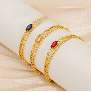 Detail of gold double-layer bracelets with marquise zircon in blue, pink, and red stones