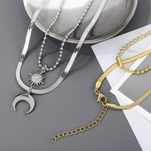 Detail of silver and gold layered necklaces with moon and star pendants on snake chains