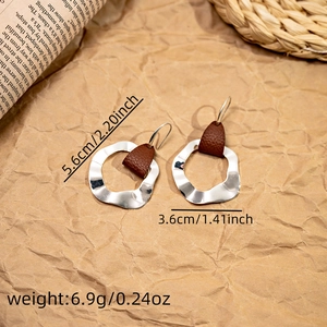Detail view of bohemian wavy silver earrings with brown leather accents and dimensions