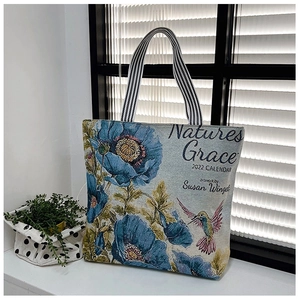Detail of floral hummingbird jacquard canvas tote bag with striped handles near a window
