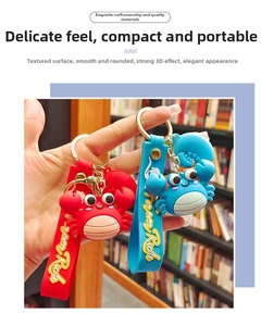 Detail view of silicone crab keychain with Forever Rich strap in red and blue colors