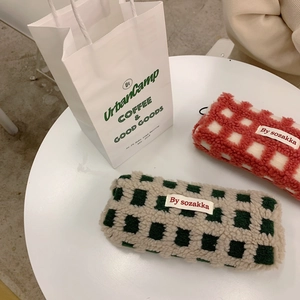 Detail of waffle lamb wool pencil cases in red and green checkerboard patterns