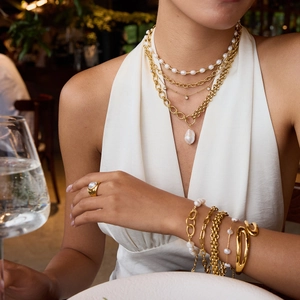 Close-up of elegant 18k gold plated layered pearl necklaces and bracelets on model
