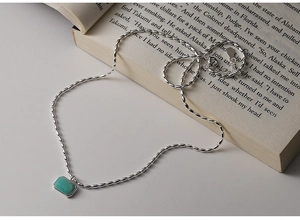 Detail of s925 silver beaded chain with a green rectangular amazonite pendant on a book
