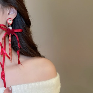 Détail de boucles d'oreilles nœud en velours rouge avec longs glands en cristal et perles