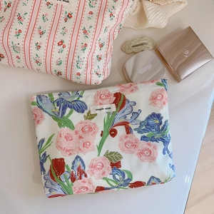 Trousses de maquillage en coton à fleurs et rayures roses sur un bureau crème