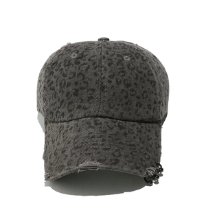 Detail of distressed dark grey leopard baseball cap with metal rings and torn edges
