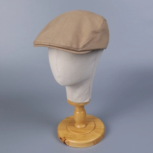 Close-up of a camel cotton flat cap with twill texture on a mannequin stand
