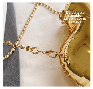 Detail of the detachable gold bead chain and lobster clasp on heart-shaped metal bag