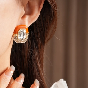 Macro view of vintage oval earring featuring orange enamel and rectangle crystal stones