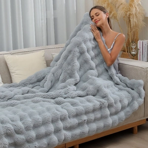 Detail of plush grey faux rabbit fur blanket with textured 3D plaid pattern and soft touch