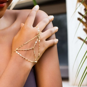 Detailed view of a gold layered hand chain with sequins and rhinestones on a female model