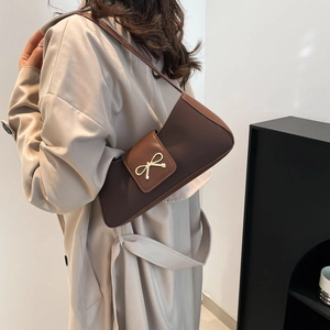 Chic two-tone brown baguette bag with metal bow detail for women in 2025 fashion style
