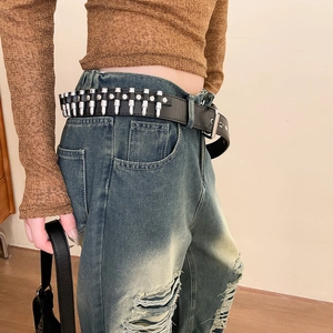 Détail d'une ceinture punk en cuir noir avec rivets balles argentés et boucle métal