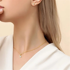 Primer plano de un elegante conjunto de collar y pendientes de plata dorada en una modelo