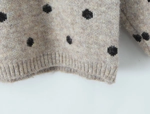 Dettaglio ravvicinato della maglia color avena con pois neri e bordo inferiore a coste